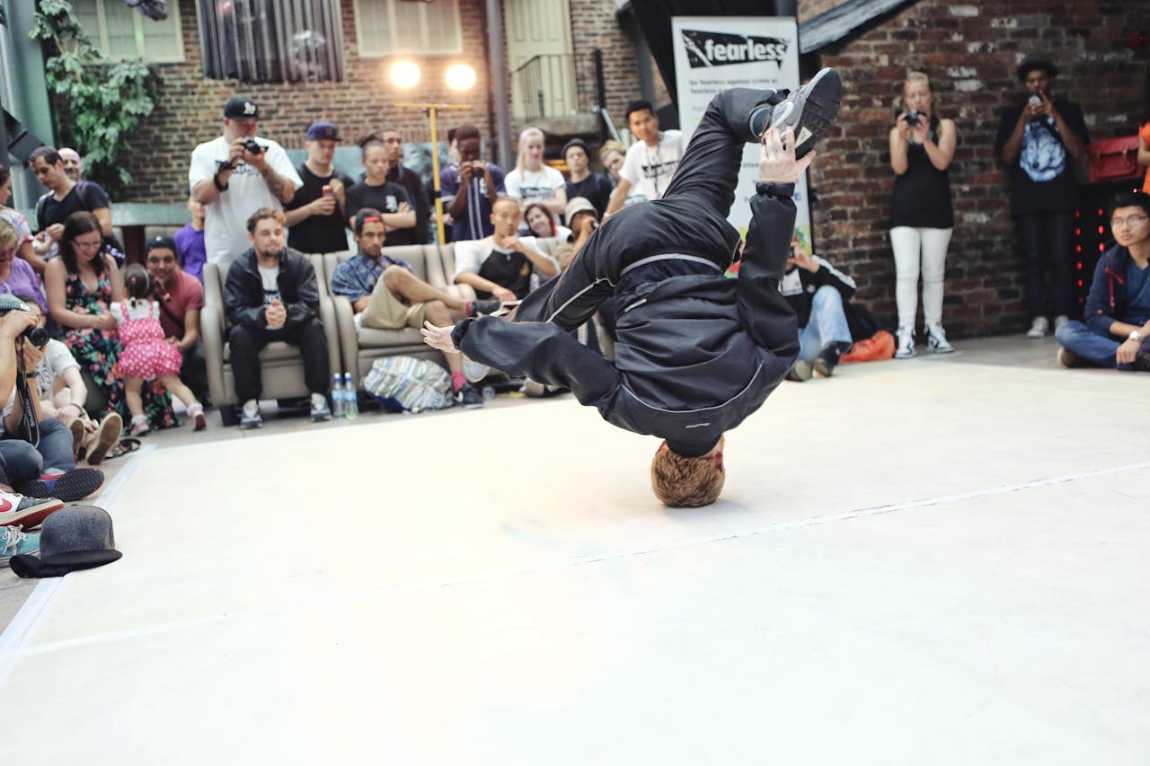 A vibrant breakdancer showcases an acrobatic move during a street performance, capturing the crowd's attention.