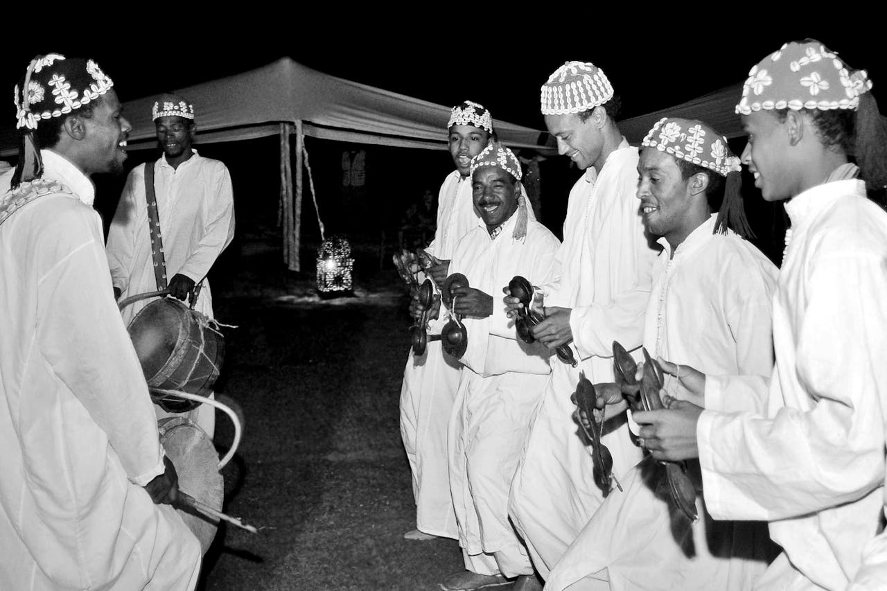 Moroccan Gnawa musicians perform at night with traditional instruments in Marrakech.