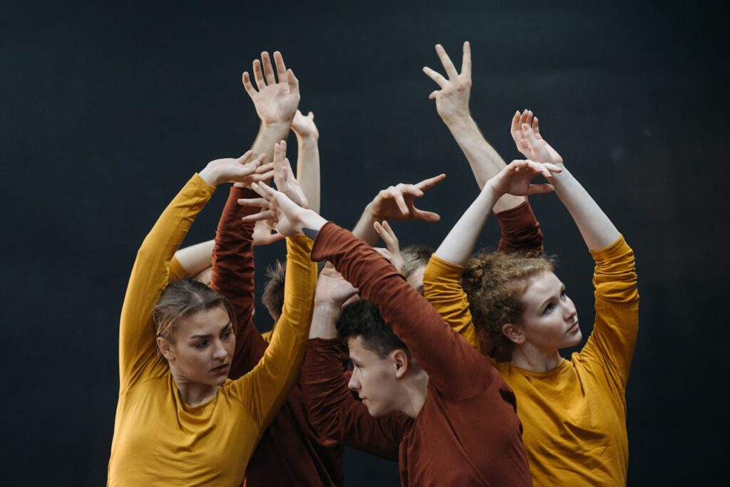 Dancers in colorful attire perform expressive contemporary dance moves indoors.